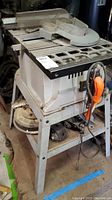 Side view of Shop Masters table saw showing metal stand, power cord, and saw table with fence and blade guard.