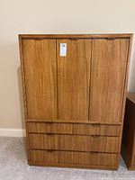 Front view of closed Drexel wood cabinet showing smooth flat panels on doors and drawer fronts with integrated handles.