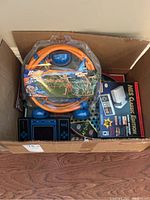 Photo of cardboard box holding all items in lot including Banzai sprinkler, NES Classic Edition box, and assorted board games.