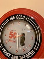 Front view of Coca-Cola wall clock showing branding and clock face with hands stopped at 6:40
