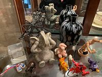 Full view of lot items including resin elephant, metal bug sculptures, glass vase, wooden shoes, miniatures