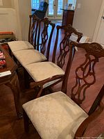 Row of carved-back dining chairs with upholstered seats