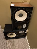 Pair of JBL L88P 88+ speakers stacked in corner with visible woofers and tweeters, missing front screens, wooden top, black cabinet.