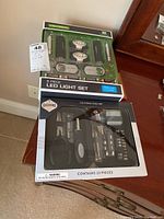 Photo showing unopened Lightgear 8-piece LED light set and Dashing 23-piece tool set on a wooden surface.