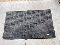 Full rectangular grey outdoor rug placed on concrete floor, showing overall condition and pattern.
