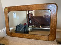 Front view of the rectangular mirror showing its wooden frame and reflective glass surface with some scratches visible.