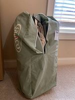 Green soft pack-n-play carrying bag with white and red Graco logo, standing upright with zipper partially open.