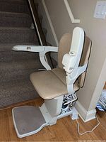 Side view of beige vinyl seat, armrests, footrest and drive unit mounted on metal rail.