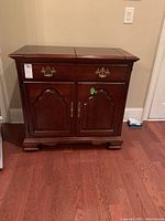 Full front view of dark wood buffet cabinet with two drawers and two doors, classic brass hardware.