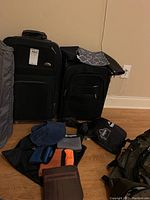 View of the Samsonite rolling suitcase, American Tourister garment bag, Wildhorn Microlite travel towels folded in mesh bags, and REI duffel bag on floor.