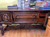 Front view showing carved wood details, two central drawers, and left side door closed