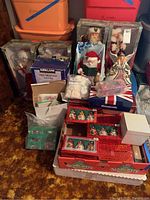 Wide view of lot showing multiple boxed Santa figurines, angel cookie jar, and ornament boxes stacked