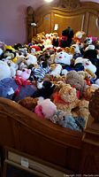 Bed fully covered with assorted stuffed teddy bears and plush animals in various colors and sizes.