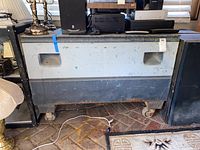 Front view of the metal utility cart showing wheels, recessed handles, and surface wear.