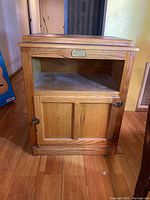 Front view of White Clad wooden cabinet showing open shelf, lower double doors, natural stained finish and brass hardware.