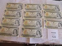 Eleven Canadian one dollar banknotes laid out on white cloth