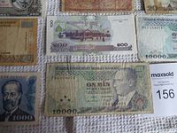 Top view of multiple world banknotes including 10000 Turkish Lira, a note with Arabic script, and a 100 denomination note.