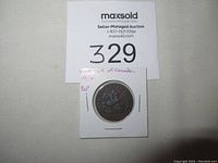 Token mounted in a white paper holder with handwritten notes 'Bank of Upper Canada 1857' and '1/2 p'. The token appears brownish with some patina indicating age and wear.