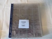 Single coin sleeve laid flat showing 20 coin pockets with blue binding and three holes for binder attachment.