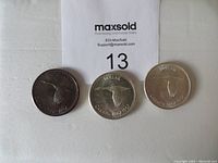 Three Canada goose design silver dollars with varying toning on white background and lot tag