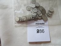 Photo showing 50 Canadian silver dimes in circulated condition packed together in a clear plastic bag with a MaxSold label.