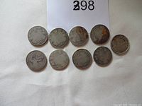 Ten very worn silver quarters laid out in two rows on white textile background, showing heavily worn faces and illegible dates. Coins have corrosion and tarnish.