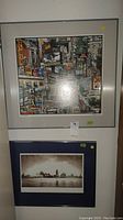 Full view of both framed art prints hung vertically on a wall, one colorful city collage and one sepia skyline.