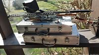 Photo showing two metal carrying cases with grilling baskets and other grilling tools stacked on top.