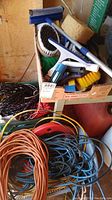 Photo showing assorted cleaning brushes, squeegees, sponges, and trigger spray bottle arranged in a box with ropes visible underneath.