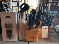 Photo showing two wooden cutlery blocks with knives inserted. Boxed M&M's dispenser and salt and pepper mill behind them.