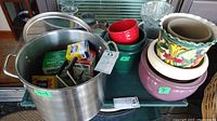 View of the entire lot showing the large aluminum pot, various canning jars, metal lids, ceramic planters of different styles and colors, green roasting pan, and glass vase.