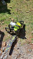 Photo of lime green and black Poulan gas chainsaw on grass and ground showing entire saw with attached 14-inch bar and chain.