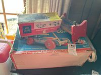 Vintage Fisher Price ride-on Volkswagen sedan toy on top of its box next to a wooden hammering toy, all showing wear.