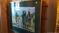 Framed watercolour painting in a dark and gold frame showing full view of artwork depicting women and child on a shore.