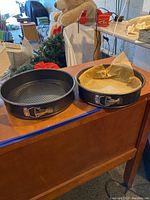 Two springform pans side by side on wooden piano top.
