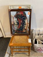 Wooden framed mirror with 'Masters Tavern Beer' advertising sign on mirror glass, resting on wooden chair with cane seat.