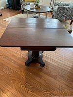 Empire style side table showing the top with two leaves and visible surface scratches and wear.