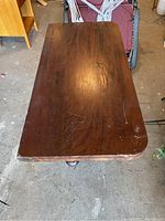 Top view showing scratches and worn finish on the brown mahogany table surface with red chocolate brown highlights.