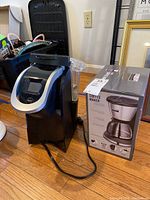 Keurig K2.0-20 coffee maker next to a boxed coffee maker on floor.