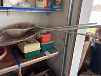 Three fishing nets with metal poles resting on top of two fishing tackle boxes and a metal utility box on a table.