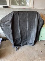 Grill covered with a black protective cover, showing full coverage and closure straps.