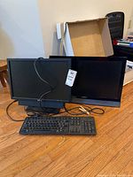 Photo showing two monitors and one keyboard on wooden floor, cables visible. Includes Vizio model M220VA monitor, Dell monitor, and wired keyboard.