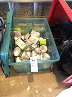 Plastic translucent green bin filled with silver 65 watt flood light bulbs and boxed LED lamp bulbs.