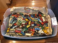 Top view of a large plastic bin filled with various Matchbox toy cars and trucks.