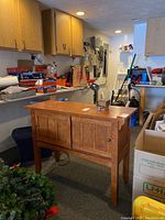 Wooden sidebar cabinet with two visible sliding doors, placed in a cluttered garage space.