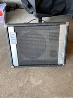 Front view of the Eminence Alpha speaker showing mesh grille and metal protective strips with labeling.