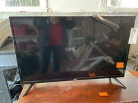 Front view of Onn 32-inch TV with remote control on top right corner of the screen.