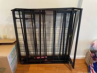 Two metal twin bed frames stacked together against a wall, showing their black metal grid structure