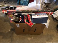 Box containing assorted holiday wrapping supplies and a snowman making kit on top