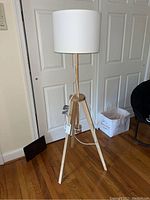 Full view of the wooden tripod floor lamp with white drum lampshade showing height and overall design.